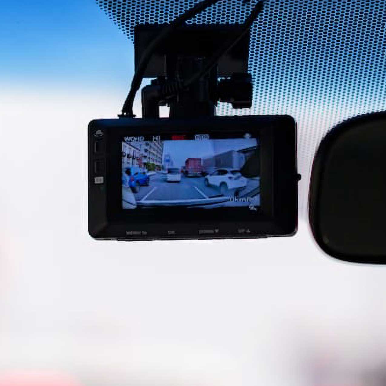フロントガラスに取り付けられ、前方の道路風景を画面に映しているドライブレコーダー